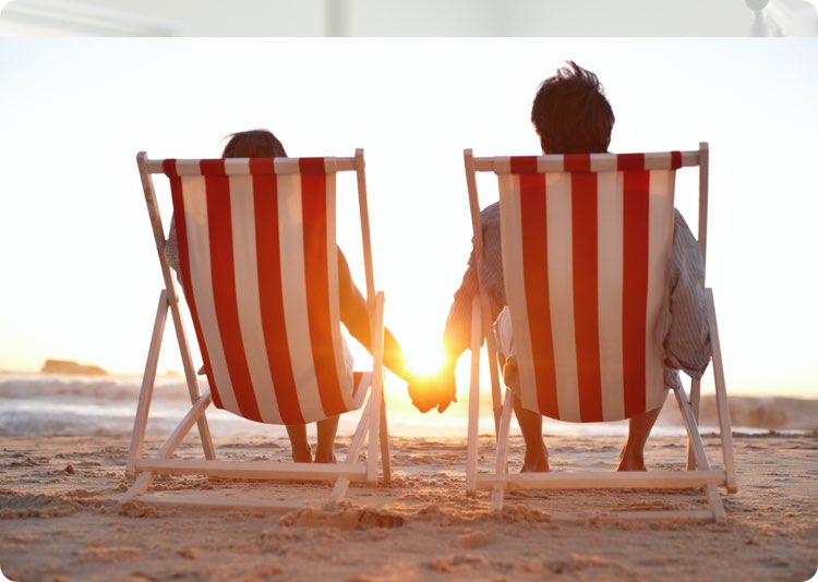 Två personer som sitter i solstol på strand